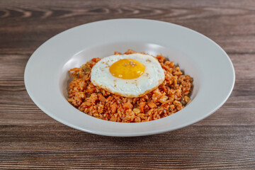 Korean food kimchi fried rice dish with fried egg on white plate