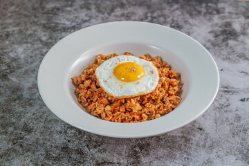 Korean food kimchi fried rice dish with fried egg on white plate