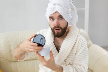 Portrait of man applying effective cream on his facial skin. Spa at home, body and skin care for male concept.