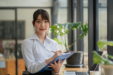 Asian young female executive reading a document in her hands while working at the office.