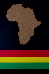 Obraz premium Black History Month concept. Africa Continent shape with traditional red, yellow and green color bar. Space for your text. Flat lay.