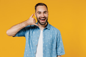 Young smiling happy cheerful consultant caucasian man 20s wearing blue shirt doing phone gesture like says call me back isolated on plain yellow background studio portrait. People lifestyle concept.