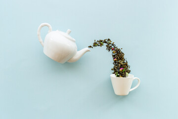 Tea background o white teapot and cup with dry tea leaves