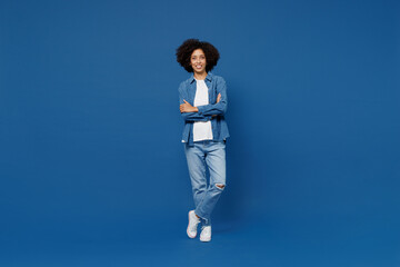 Full body young smiling happy black woman in casual clothes shirt white t-shirt hold hands crossed folded look camera isolated on plain dark blue background studio portrait. People lifestyle concept.