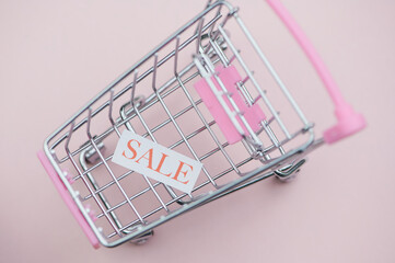 the word sale on a white paper in a miniature shopping cart