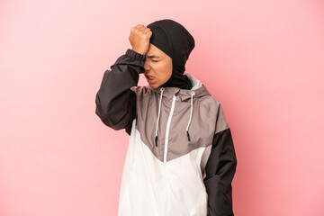 Young Arab woman with sport burqa isolated on pink background forgetting something, slapping...