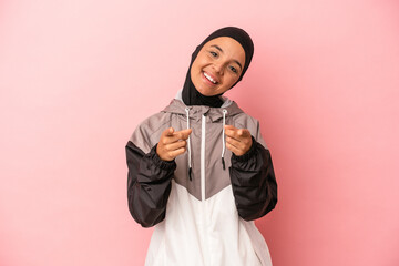 Young Arab woman with sport burqa isolated on pink background cheerful smiles pointing to front.