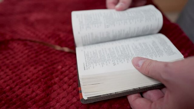A closeup shot of male hands placing the bookmark on the needed page of the Bible and closing it