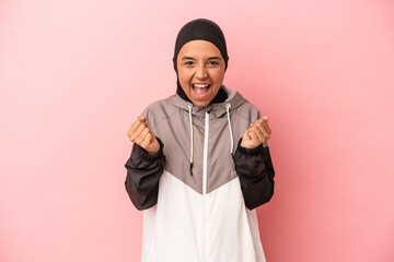 Young Arab woman with sport burqa isolated on pink background cheering carefree and excited....