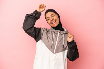 Young Arab woman with sport burqa isolated on pink background celebrating a special day, jumps and...