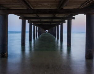 Metal supports of the pier at dawn. View of the pillars under th
