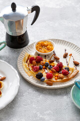 Breakfast crepes with berries and jam coffee cups pot