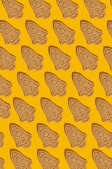 Pattern of cookies in the form of a rocket on a yellow background.