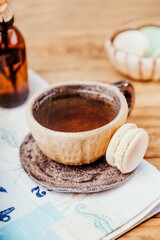 Ceramic cup with tea and macaron on a wooden table, copy space