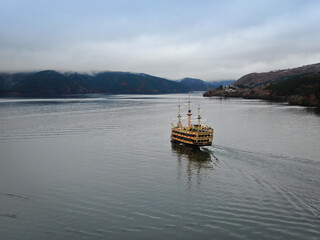 Fototapeta na wymiar A semi-antique wooden tourist ship sails against the backdrop of a Japanese landscape