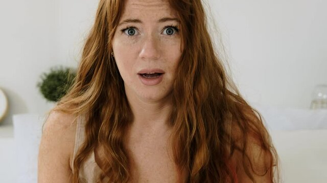 Young woman wakes up abruptly and looks at the alarm clock in her smartphone.  girl overslept and panics that she was late for work. Waking up in morning in bedroom