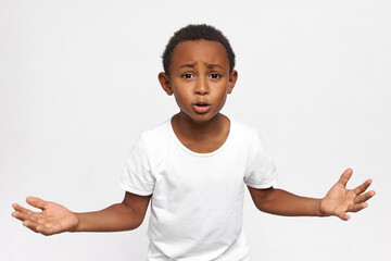 Horizontal portrait of cool African American boy arguing, gesticulating while talking emotionally, reaching hands up, proving he’s right, giving arguments. Body language, gestures, emotions