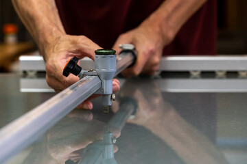 Cutting glass with a special tool. Glass cutter. A master in the workshop cuts glass according to the customer's dimensions.