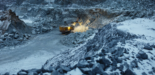 Quarry excavator during night work in a limestone quarry in winter conditions, panorama.