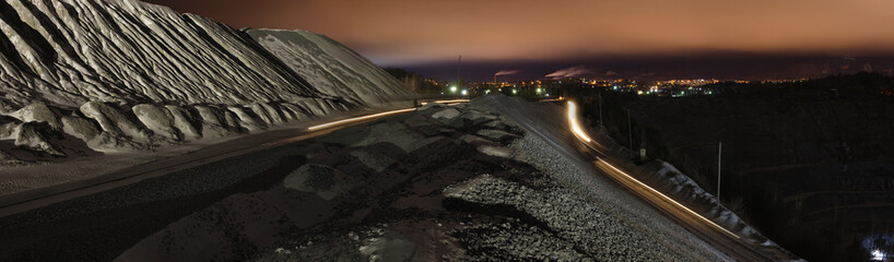Panoramic image of night work near a limestone quarry with blurred  traces headlights from moving...