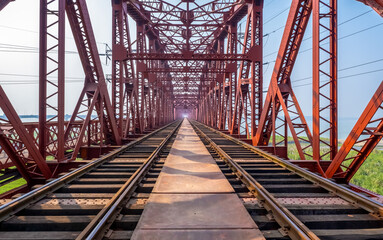 Old steel railway bridge over a wide river. Iron bridge fastened with steel rivets. Railway line.
