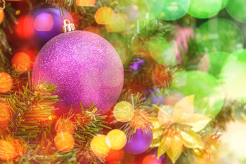 Christmas bokeh lights on a Christmas tree with purple balls background. New Year composition with copy space