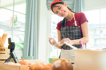 A Beautiful asian woman is making bakery ,   live streaming or recording video on social media in...