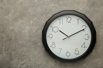 Black wall clock on the grey background.