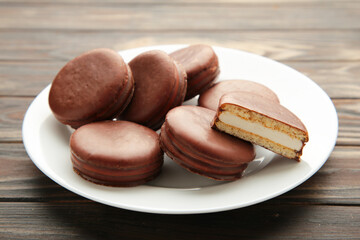 Choco pie chocolate coated snacks in plate on brown wooden background.