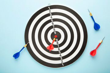 Dart board with red darts on blue background.