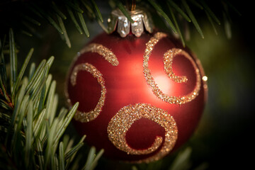 Gros plan sur une boule de noel rouge suspendu à une branche