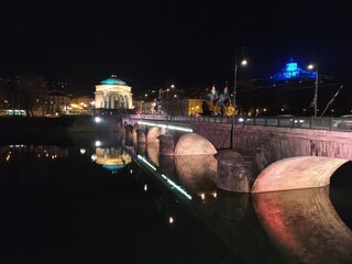 Foto notturna di Torino, gran Madre che si riflette su fiume Po, con sfondo del monte cappuccini