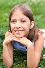 Fototapeta premium a cheerful girl of 8-10 years old plays on a green meadow on a warm summer day, walks in the fresh air, joy and happiness