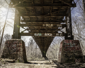 Abandoned rusted railway bridge with graffitis on a sunny day