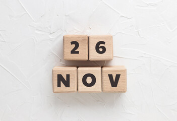 Text 26 NOV (November) on wooden cubes on white textured putty background. Date. Black friday. Square wood blocks. Top view, flat lay.