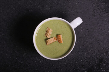 spinach puree soup with crackers is on the table