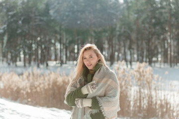 Pretty young blond woman, dressed warmly, with a scarf and mittens. Winter time outside