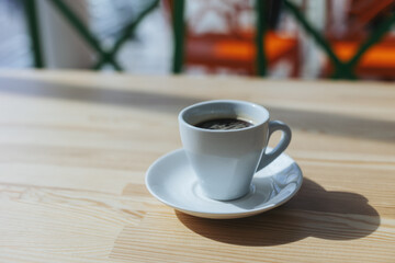 Cup of black coffee on a wooden table in a cafe.