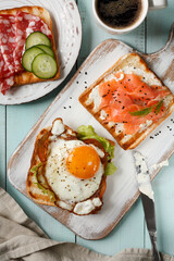 Breakfast with coffee and sandwiches on toasted bread with sausage and cucumber, cottage cheese and lightly salted salmon, fried egg and tomato