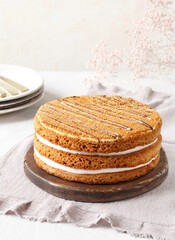 A whole honey cake with sour cream before serving with plates and gypsophila in the background