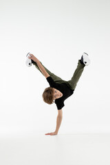 Isolated young Russian teenage boy in black t-shirt hip hop break dancer dancing in studio in white...