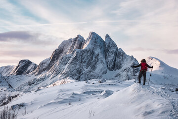 Naklejka na ściany i meble Mountaineer standing on Segla mountain with majestic snowy mount on winter at Senja island