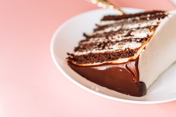 Piece of puff chocolate cake on round plate with small fork