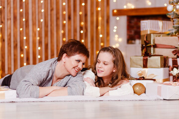 smiling woman and teenage girl lie on white blanket for Christmas