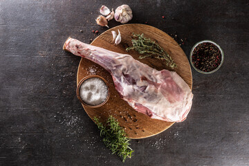 Raw lamb leg with spices, salt, herbs and garlic.