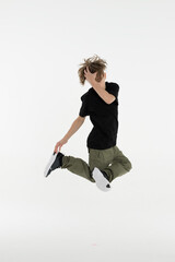 Fototapeta na wymiar Isolated young Russian teenage boy in black t-shirt hip hop break dancer dancing in studio in white background, jumping and touching his head