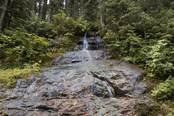 small stream trickles down onto large open colorful rock