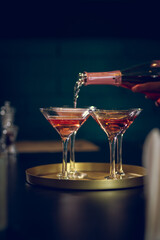 A bottle of Champaign being poured into glasses on the dark background 