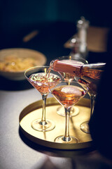 A bottle of Champaign being poured into glasses with some dishes on the background 