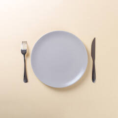 Knife fork and empty plate on a yellow background.